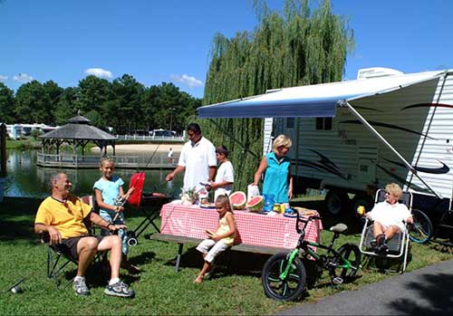Multi-generational family camping near water having BBQ at Wilderness Presidential Resort