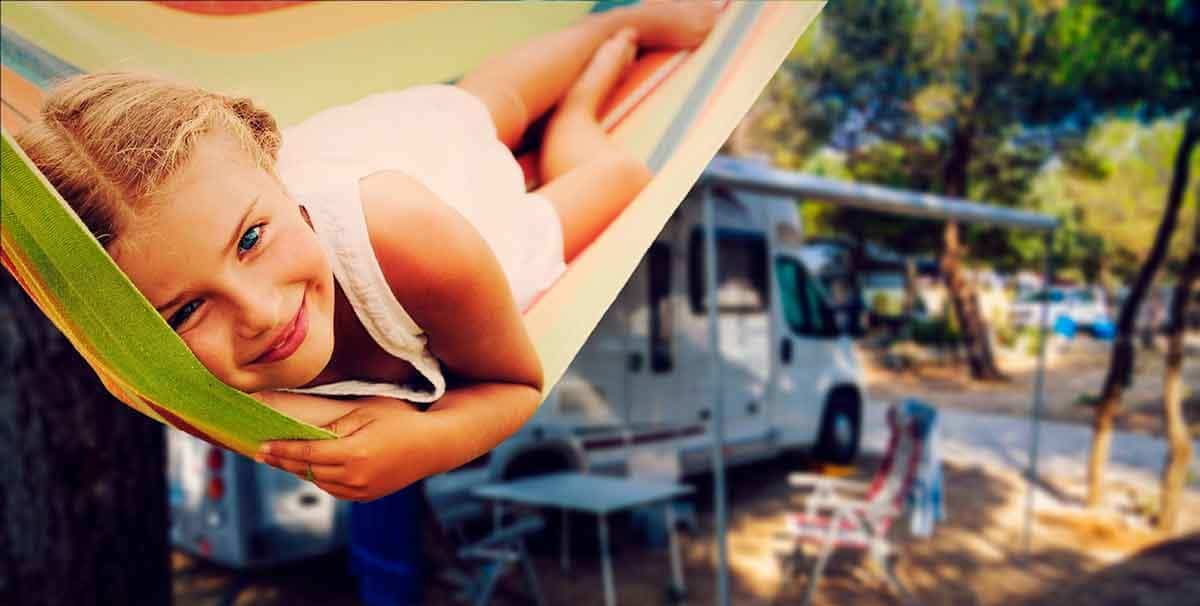 Young girl relaxing in hammock next to rv campsite in woods