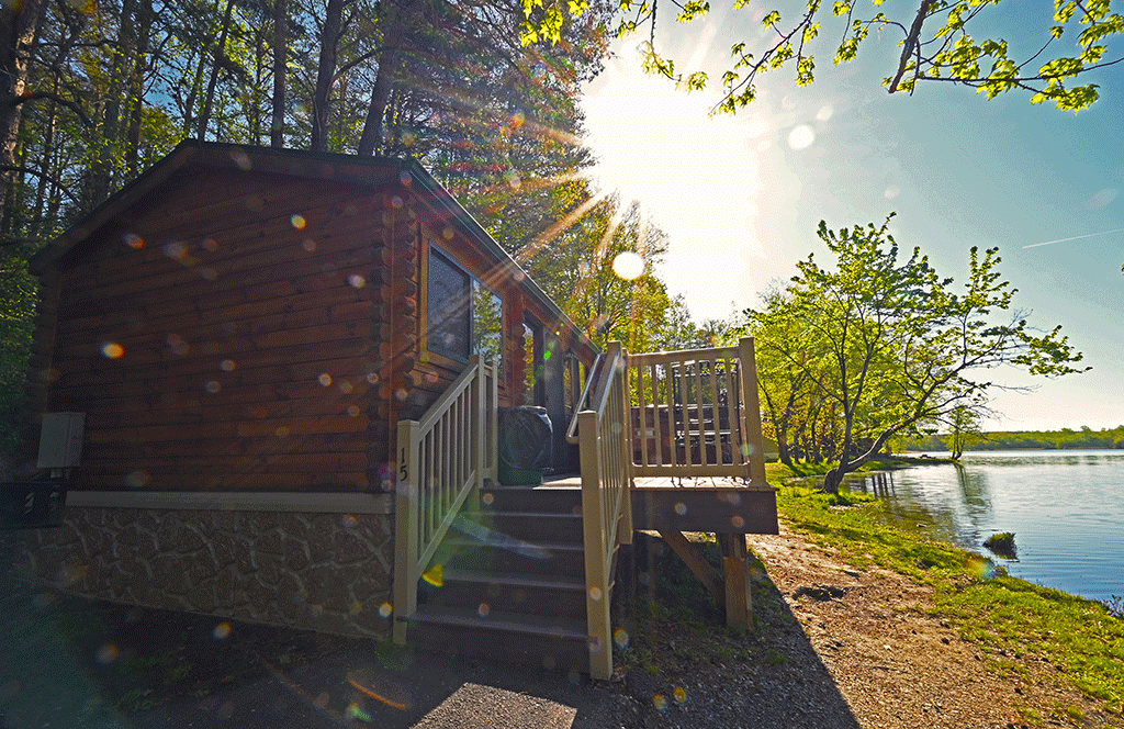 Sunrise over camp cabin with hot tub on the lake in Spring.